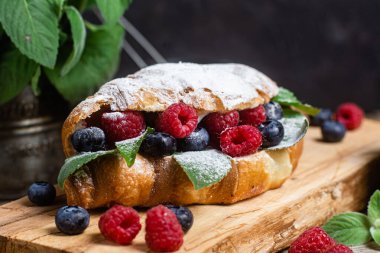 Tahtada ahududu, yaban mersini ve krem peynirli kruvasan.