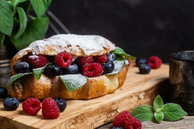 Tahtada ahududu, yaban mersini ve krem peynirli kruvasan.