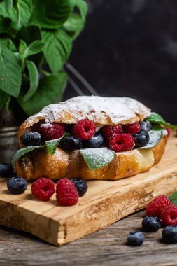 Tahtada ahududu, yaban mersini ve krem peynirli kruvasan.