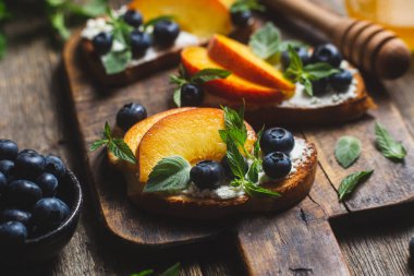 White bread sandwich with peaches, blueberries on a wooden board