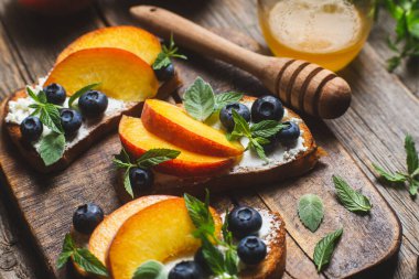 White bread sandwich with peaches, blueberries on a wooden board