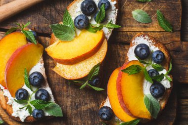 White bread sandwich with peaches, blueberries on a wooden board