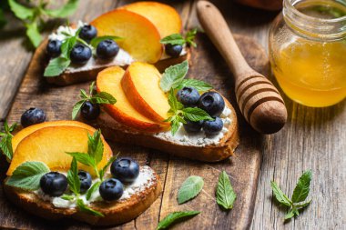 White bread sandwich with peaches, blueberries on a wooden board