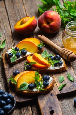 White bread sandwich with peaches, blueberries on a wooden board