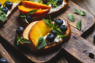 White bread sandwich with peaches, blueberries on a wooden board