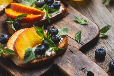 White bread sandwich with peaches, blueberries on a wooden board