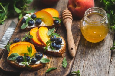 White bread sandwich with peaches, blueberries on a wooden board
