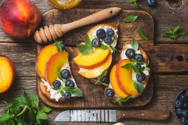White bread sandwich with peaches, blueberries on a wooden board