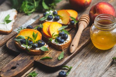 White bread sandwich with peaches, blueberries on a wooden board