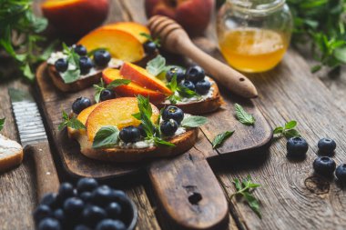 White bread sandwich with peaches, blueberries on a wooden board