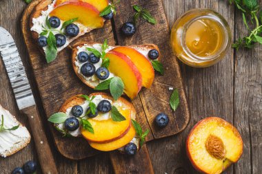 White bread sandwich with peaches, blueberries on a wooden board