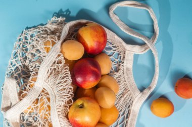 Parlak bir arka planda, ekolojik bir çantada kayısı. Satın Al