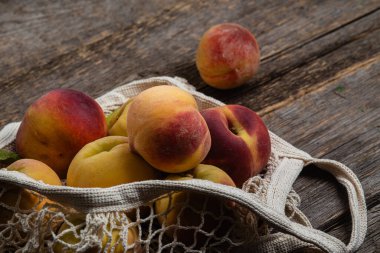 Olgun şeftaliler ahşap arka planda, eko torba içinde.