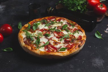 Jambonlu pizza, domates ve arka planda mozzarella.
