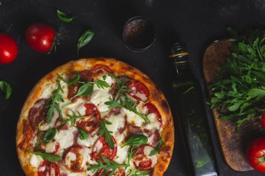 Jambonlu pizza, domates ve arka planda mozzarella.