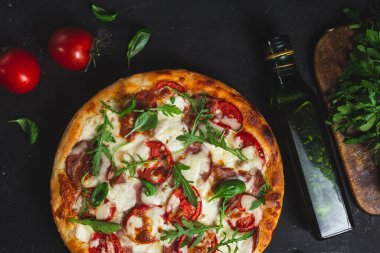 Jambonlu pizza, domates ve arka planda mozzarella.