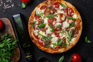 Jambonlu pizza, domates ve arka planda mozzarella.