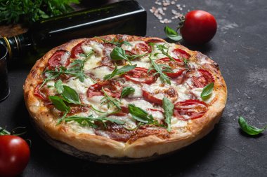 Jambonlu pizza, domates ve arka planda mozzarella.