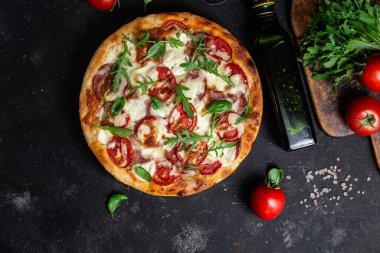 Jambonlu pizza, domates ve arka planda mozzarella.