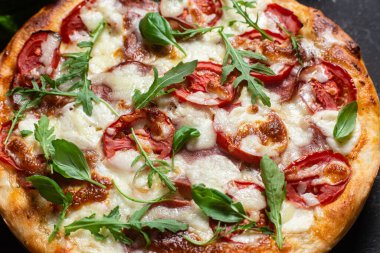 Jambonlu pizza, domates ve arka planda mozzarella.