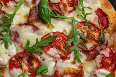 Jambonlu pizza, domates ve arka planda mozzarella.