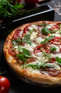 Jambonlu pizza, domates ve arka planda mozzarella.