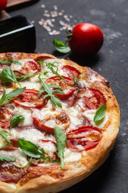 Jambonlu pizza, domates ve arka planda mozzarella.