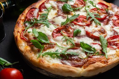 Jambonlu pizza, domates ve arka planda mozzarella.