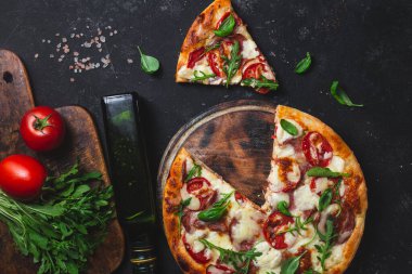 Jambonlu pizza, domates ve arka planda mozzarella.