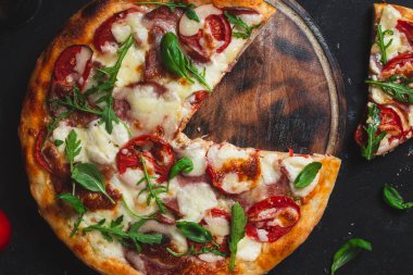 Jambonlu pizza, domates ve arka planda mozzarella.