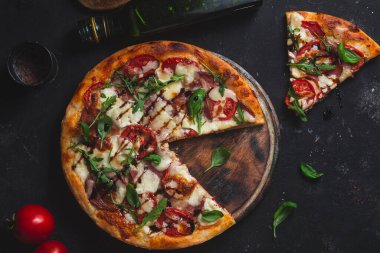 Jambonlu pizza, domates ve arka planda mozzarella.