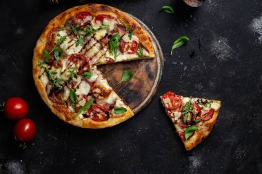 Jambonlu pizza, domates ve arka planda mozzarella.