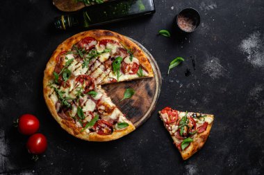 Jambonlu pizza, domates ve arka planda mozzarella.