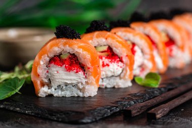 Çeşitli suşiler, koyu bir arka planda yuvarlanıyor.