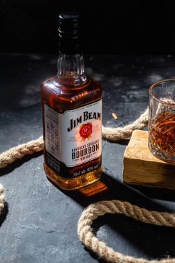 Karanlık bir arka planda bir şişe viski Jim Beam. Burbon