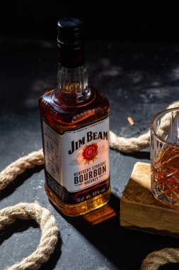 Karanlık bir arka planda bir şişe viski Jim Beam. Burbon