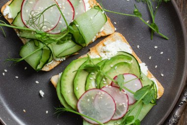 Krem peynirli beyaz ekmek tostu, avokado, salatalık ve turp.