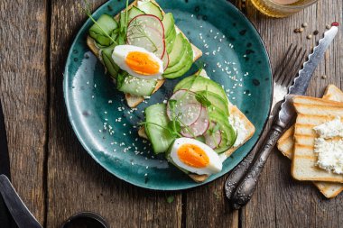 Kahvaltıda. Krem peynirli sandviç, avokado, salatalık ve haşlanmış yumurta.