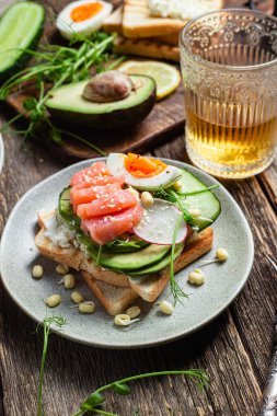 Krem peynirli tost, somon, yumurta, avokado, tabakta salatalık.