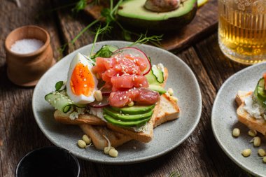 Krem peynirli tost, somon, yumurta, avokado, tabakta salatalık.