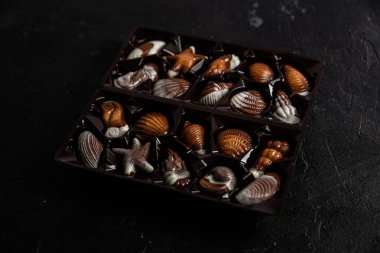 Koyu arkaplanda kabuk şeklinde çikolatalı şekerler.