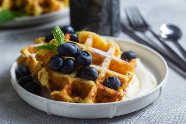 Belgian waffles with sour cream and blueberries in a plate clipart