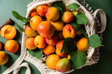 Tek bir arkaplanda, bir sicim torbasında olgun kayısılar.