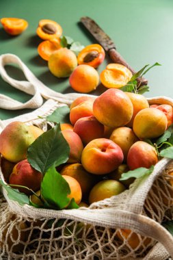 Tek bir arkaplanda, bir sicim torbasında olgun kayısılar.