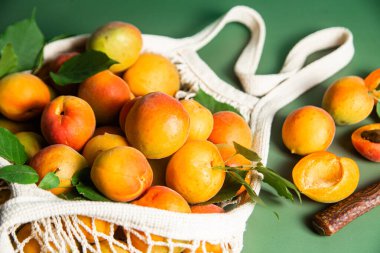 Tek bir arkaplanda, bir sicim torbasında olgun kayısılar.