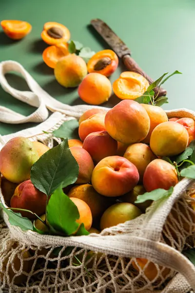 Tek bir arkaplanda, bir sicim torbasında olgun kayısılar.