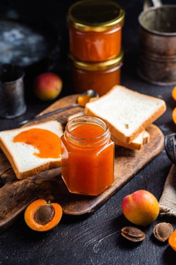 Masadaki cam kavanozda olgun kayısı reçeli.