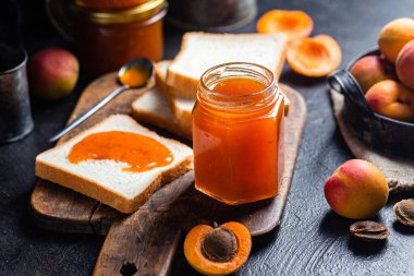 Masadaki cam kavanozda olgun kayısı reçeli.