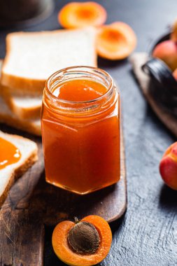 Masadaki cam kavanozda olgun kayısı reçeli.