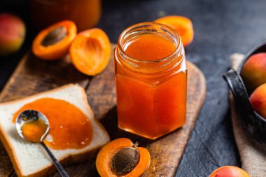 Masadaki cam kavanozda olgun kayısı reçeli.